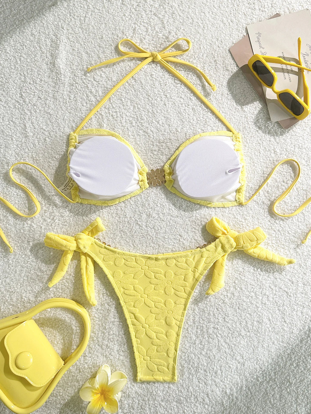 Yellow bikini set with sunglasses and flowers on a light background